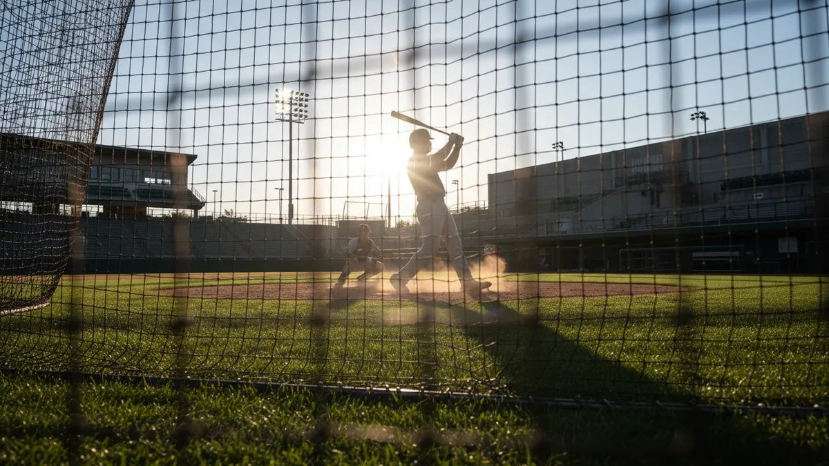 Bateador practica antes de un partido de MLB, visto a través de una red.